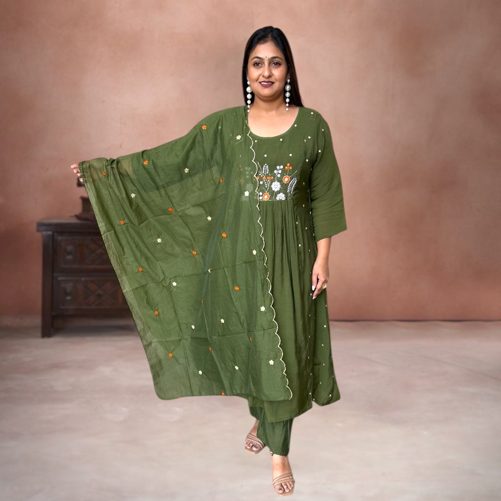 Woman wearing a green traditional outfit with embroidery against a brown background