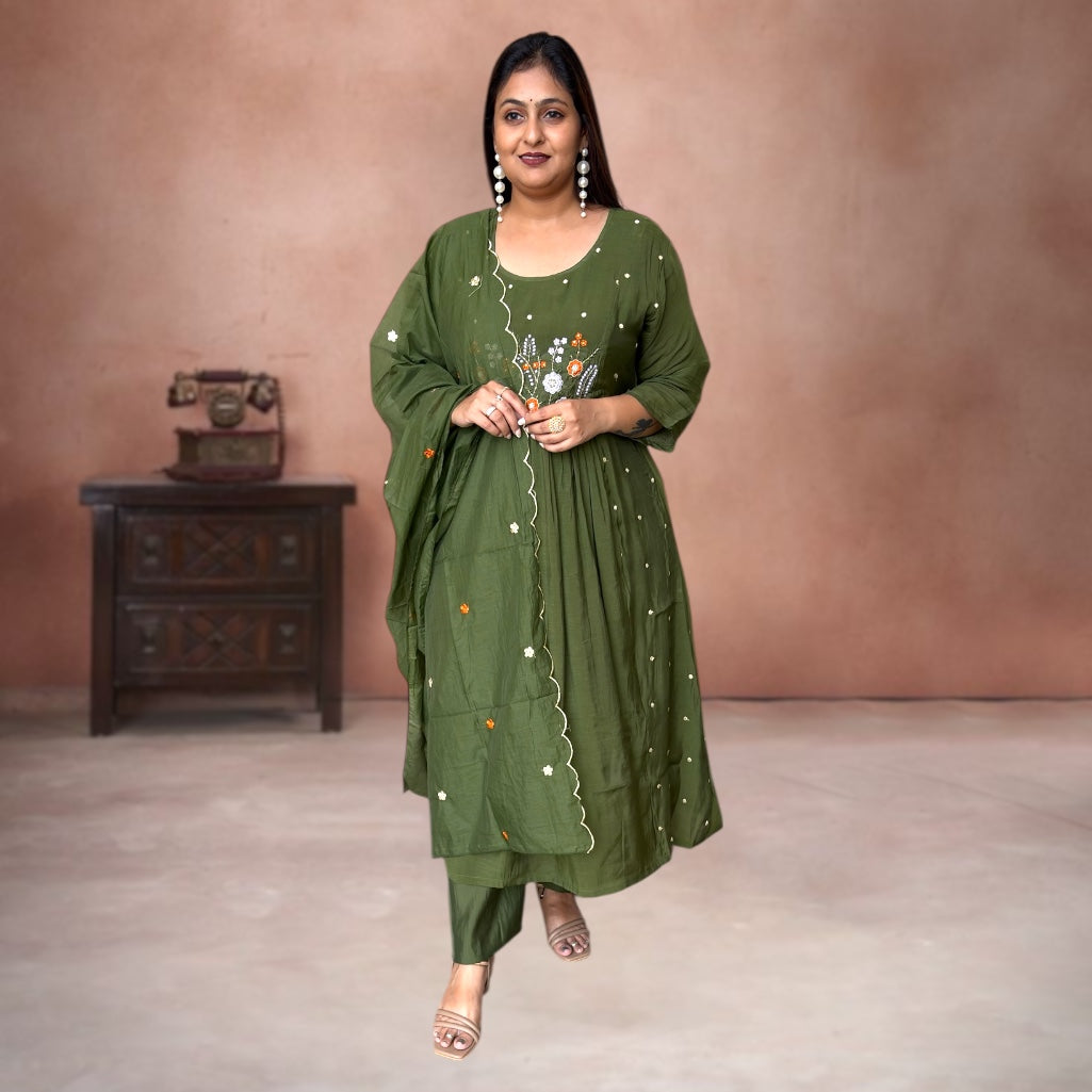 Woman wearing a green embroidered traditional outfit against a brown background